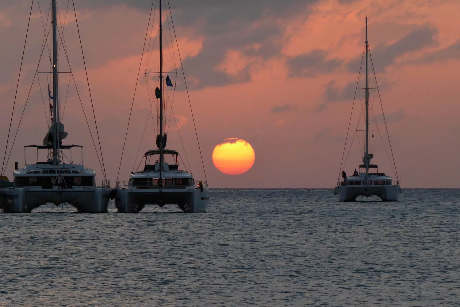 Le soleil se rapproche de l'horizon dans cette scène de coucher de soleil des catamarans sur l'eau au large d'Anguilla.