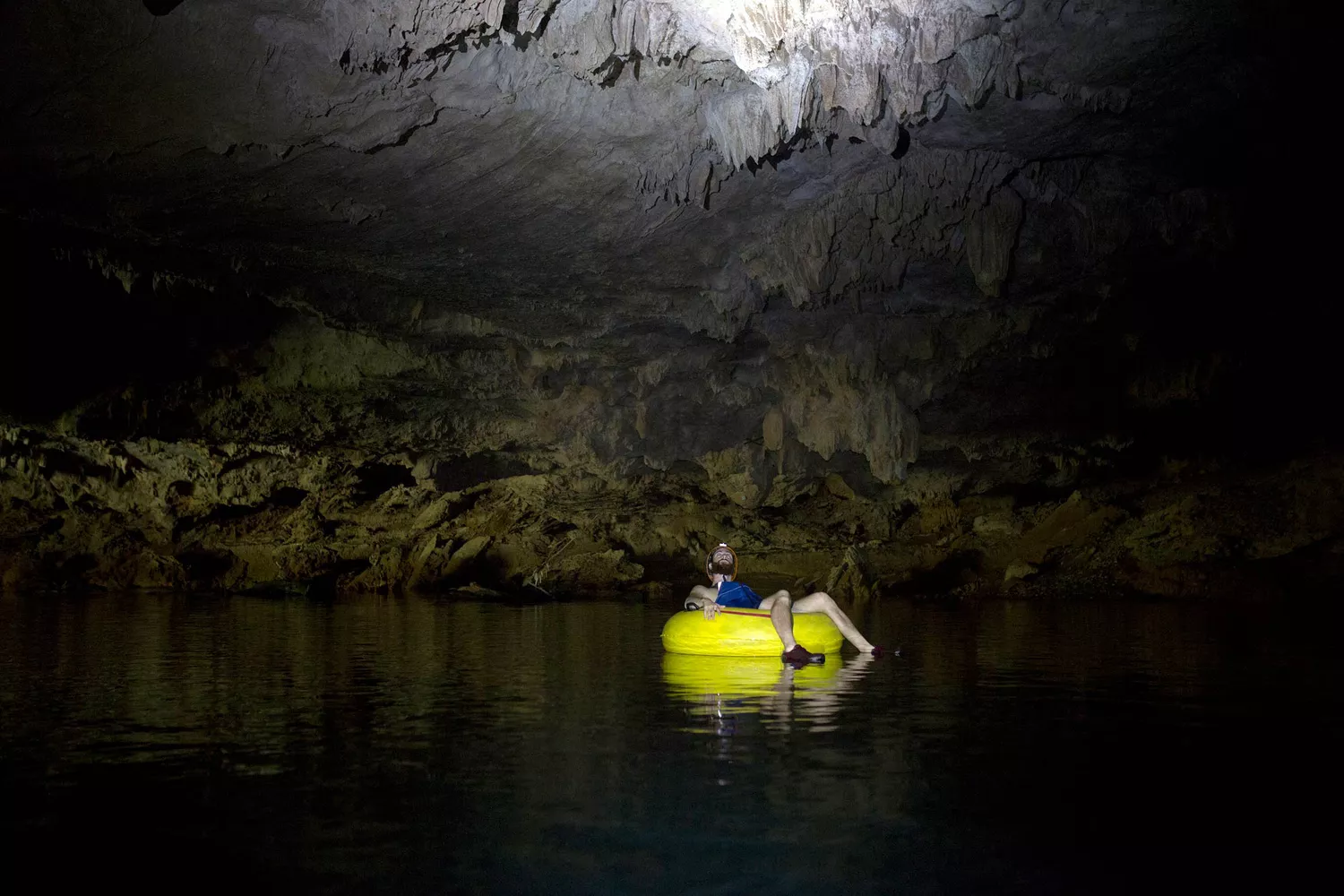 Homme faisant du tubing dans une grotte au Belize