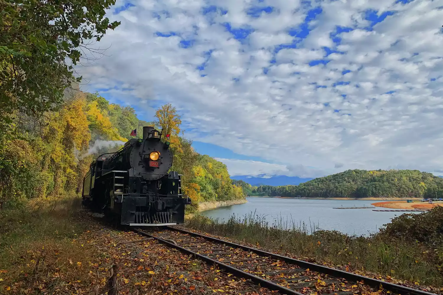 un train noir passant près d'un lac dans les Great Smoky Mountains