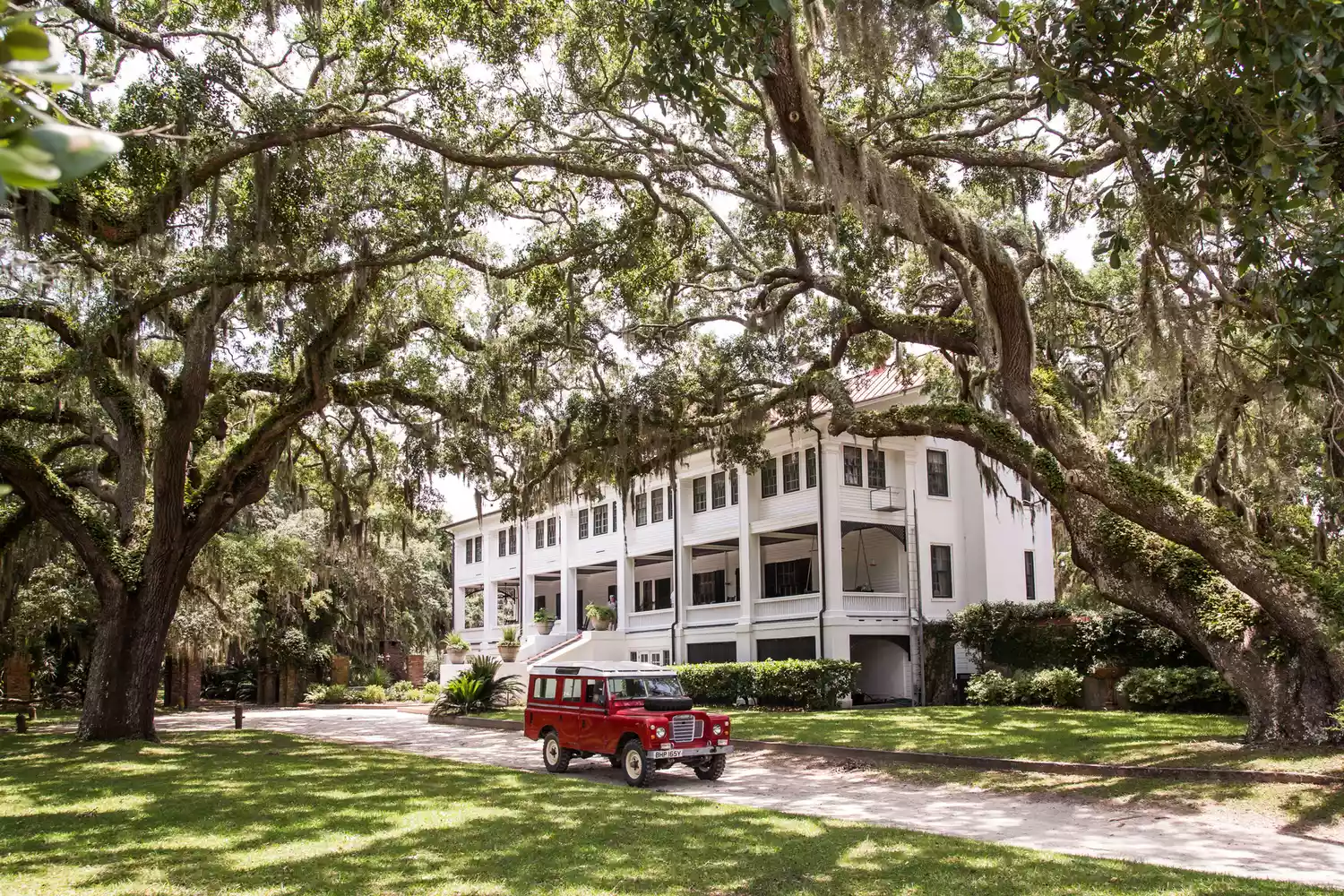 A red classic car driving in front of the Greyfield Inn