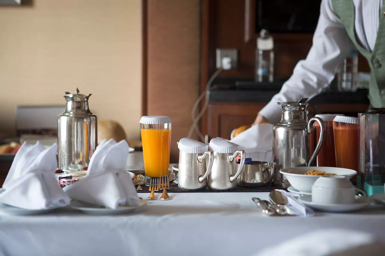 table du petit-déjeuner dans une chambre d'hôtel avec des fruits et des jus, du café et du thé