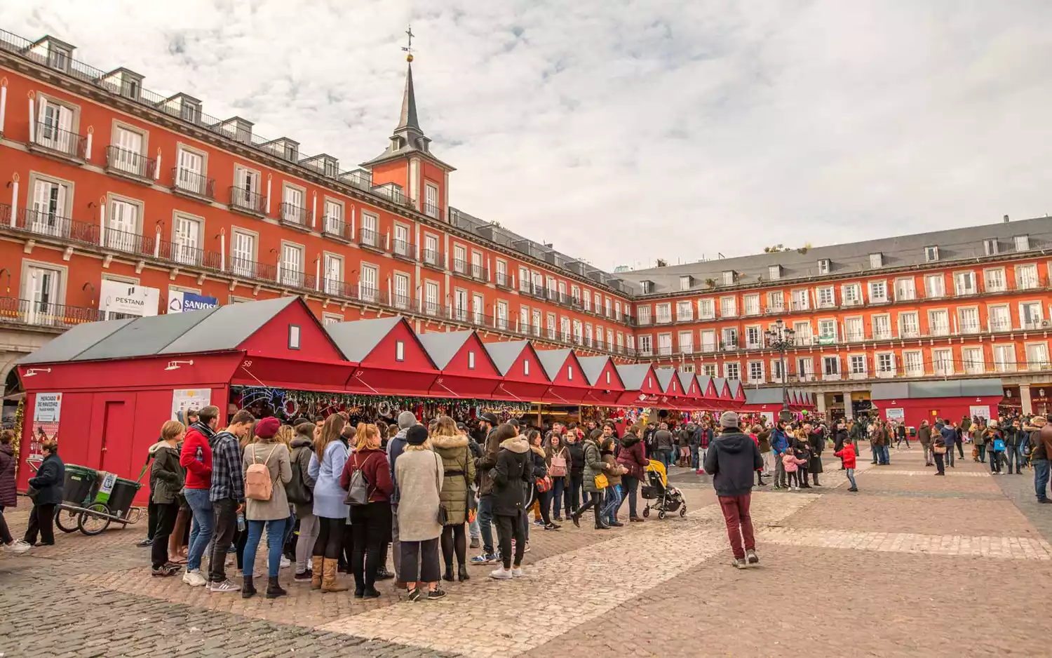 A series of red Christmas market stalls lines the interior of Madrid's Plaza Mayor.