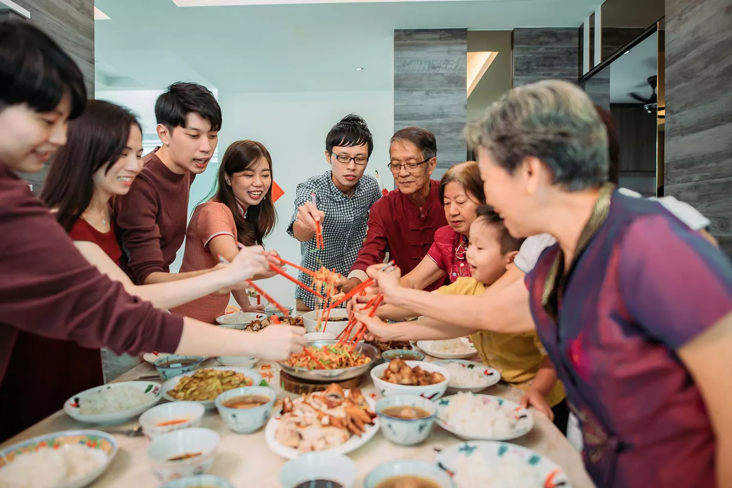 Famille célébrant la veille du Nouvel An lunaire avec une salade de poisson cru Lou Shang pendant le dîner de retrouvailles