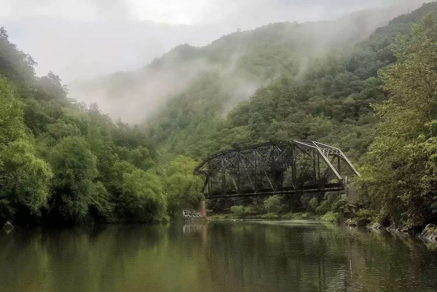 Vapeur s'élevant des sources chaudes dans les montagnes au-dessus d'un pont en acier