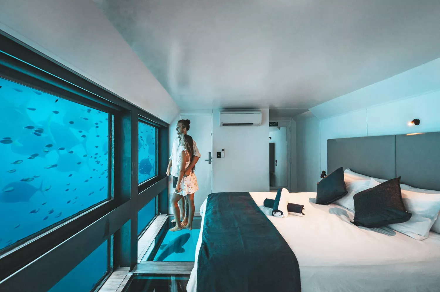 Couple in an underwater hotel room looking out window