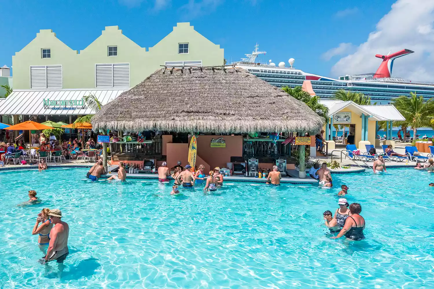 Personnes dans un bar de piscine à Margaritaville Grand Turk avec un bateau de croisière en arrière-plan